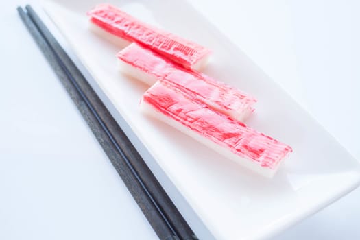 Crab sticks group with chopsticks on white background, stock photo