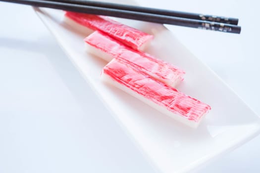 Crab sticks group with chopsticks on white plate, stock photo