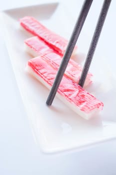 Crab sticks group and wood chopsticks on white plate, stock photo