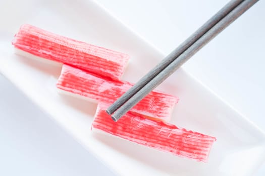 Set of crab sticks with chopsticks on white background, stock photo