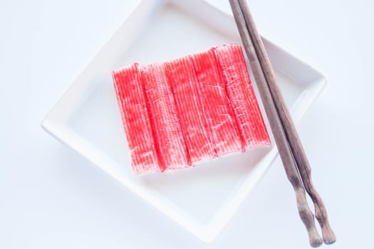 Set of crab sticks with chopsticks on white plate, stock photo