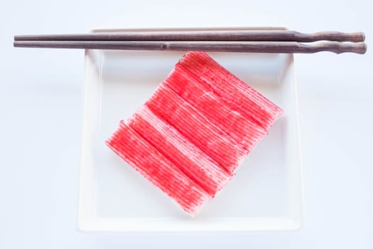 Set of crab sticks with wood chopsticks on white plate, stock photo