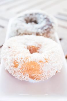 Vanilla and chocolate coconut donuts serving on white plate, stock photo