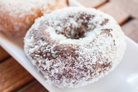 Close up chocolate coconut donut on white plate, stock photo