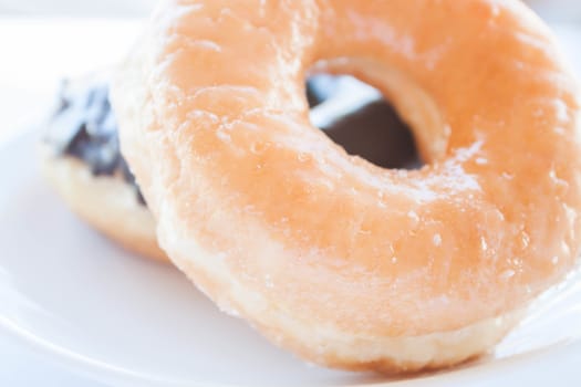 Sugar and chocolate donuts on white dish, stock photo