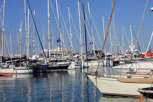 Pleasure boats and yachts moored in the sheltered water of a marina under a sunny blue summer sky