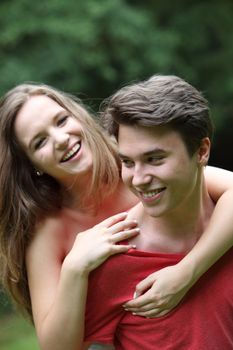 Laughing romantic young teenage couple in an affectionate embrace having fun outdoors in a garden or park