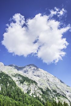 Mountain in the Austrian Alps with white cloud on blue sky