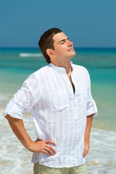 Handsome man enjoy vacation on a beach, with blue sea on background 