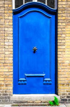 Closed blue entrance door in brick wall