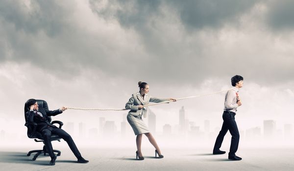 Image of three businesspeople pulling rope against city background