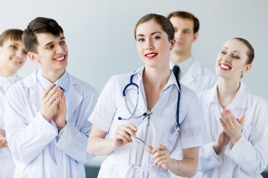 Attractive female doctor in uniform congratulated by colleagues