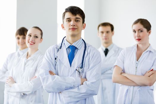 Young doctor in uniform and colleagues at background