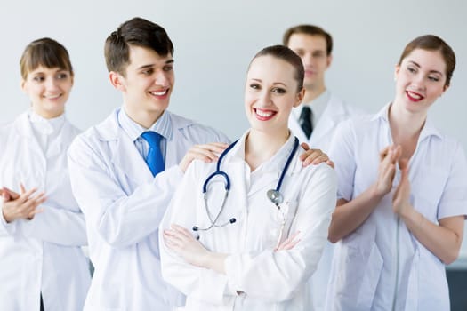 Attractive female doctor in uniform congratulated by colleagues