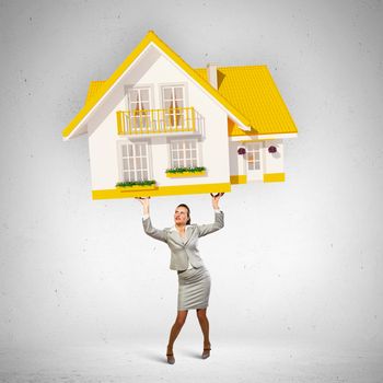 Image of businesswoman holding model of house above head
