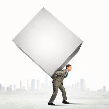 Image of businessman carrying big white cube on his back