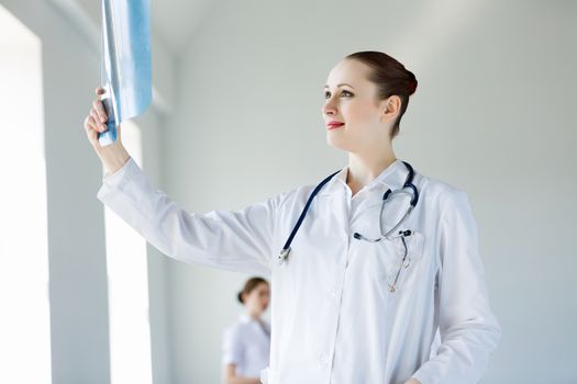 Attractive young female doctor examining x-ray results