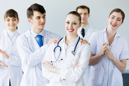 Attractive female doctor in uniform congratulated by colleagues