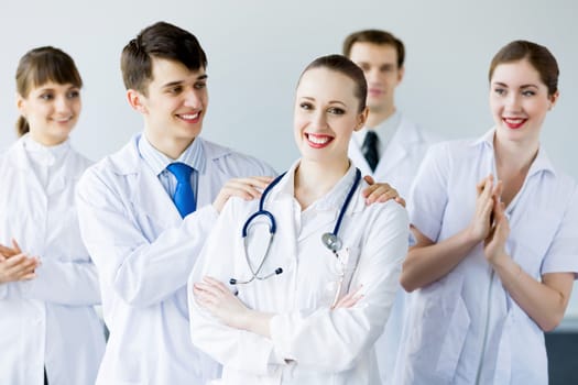 Attractive female doctor in uniform congratulated by colleagues