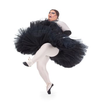 Overweight drag queen dancing in a tutu nimbly balancing on tiptoe with his foot raised in a fun caricature of a female ballet dancer, on white