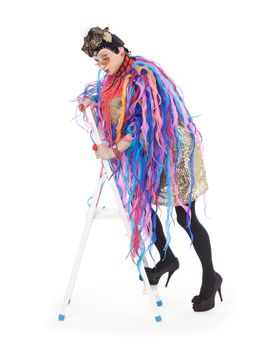 Fashion conscious drag queen in a glitzy gold dress, high heeled stilettos and with streamers performing in a show, isolated on white