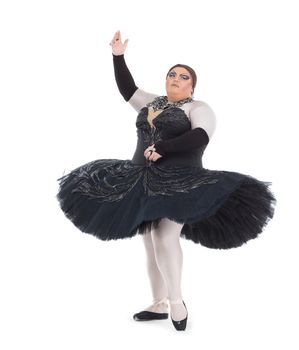 Overweight drag queen dancing in a tutu nimbly balancing on tiptoe with his foot raised in a fun caricature of a female ballet dancer, on white