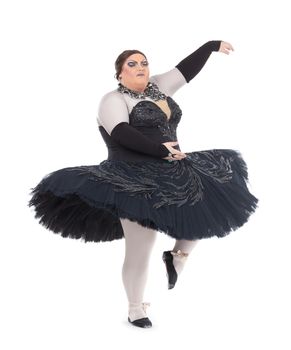 Overweight drag queen dancing in a tutu nimbly balancing on tiptoe with his foot raised in a fun caricature of a female ballet dancer, on white