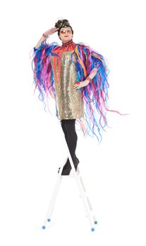 Fashion conscious drag queen in a glitzy gold dress, high heeled stilettos and with streamers performing in a show, isolated on white