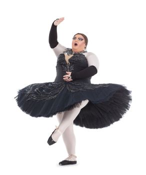 Overweight drag queen dancing in a tutu nimbly balancing on tiptoe with his foot raised in a fun caricature of a female ballet dancer, on white