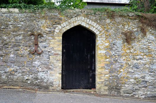 Old black wooden door surrounded by weathered stone in the historic town of Arundel, Sussex, England.