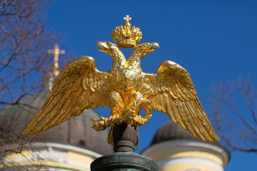 golden double-headed eagle on a background of blue sky and the domes of the church