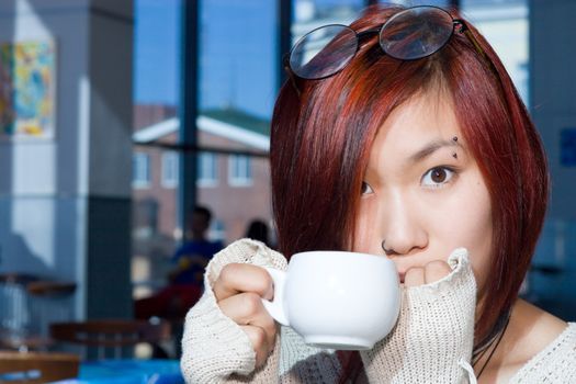 Cafe. Pretty girl having a cup of coffee with a piece of chocolate.