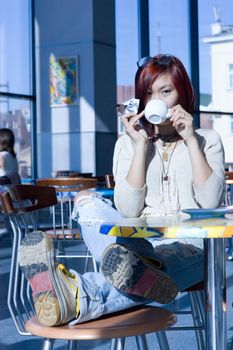 Cafe. Pretty girl having a cup of coffee with a piece of chocolate.