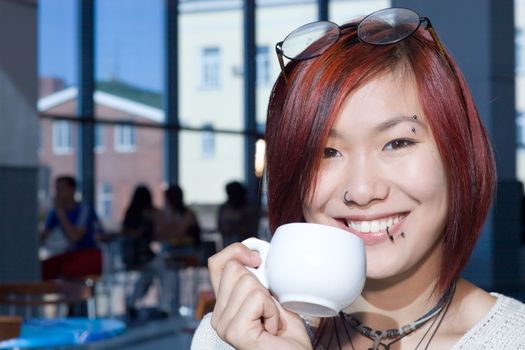 Cafe. Pretty girl having a cup of coffee with a piece of chocolate.