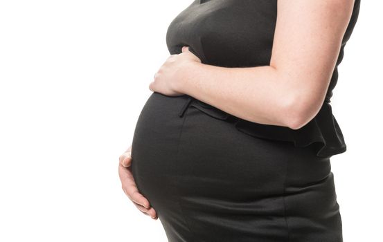 Close up of pregnant woman holding her hands around belly on white background