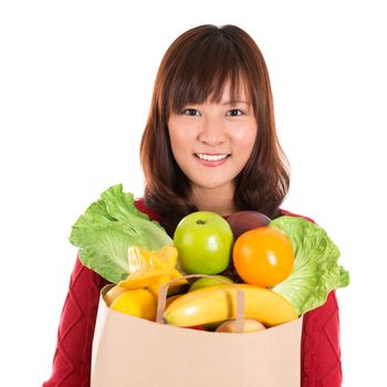 Happy grocery shopper. Smiling young Asian woman holding paper shopping bag full of groceries isolated on white.