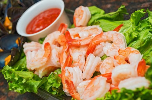 A colorful dish of cooked chilled shrimp with lettuce leaves