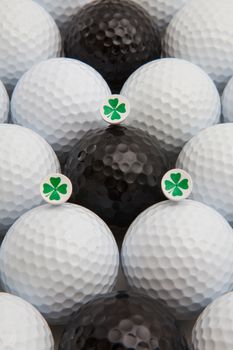 Different golf balls and wooden tees with four leaf clovers