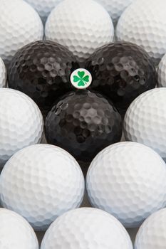 Different golf balls and wooden tee with four leaf clover