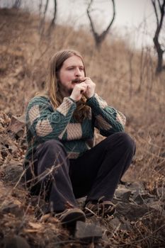 Young man relaxing outdoors playing on a humus (Jews Harp)