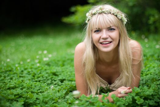 Summer. Portrait of  blonde girl with blue eyes having rest at clover meadow