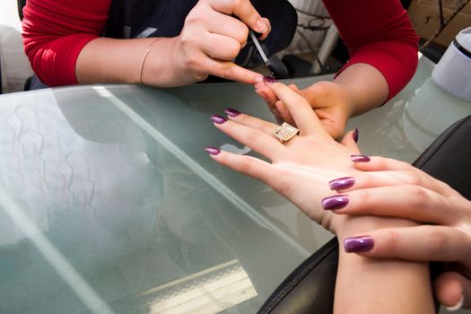 Manicurist treating customer at beauty salon 