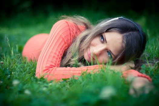 Relaxed young woman listening musi cat clover meadow