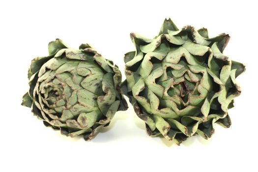 two whole artichokes on a light background