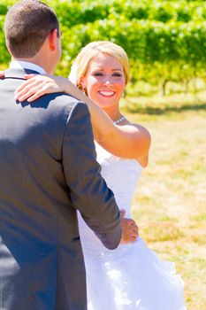 A bride and groom pose for portraits on their wedding day at a winery vineyard outdoors in oregon.