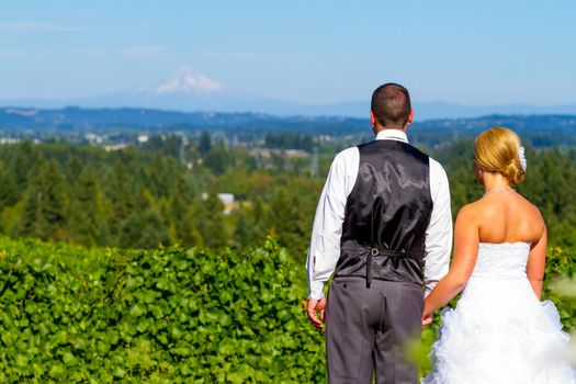 A bride and groom enjoy a view of mount hood in the background from this high elevation winery vineyard in Oregon just outside of Portland.