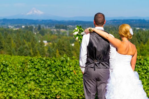 A bride and groom enjoy a view of mount hood in the background from this high elevation winery vineyard in Oregon just outside of Portland.