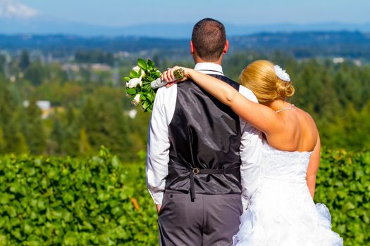 A bride and groom enjoy a view of mount hood in the background from this high elevation winery vineyard in Oregon just outside of Portland.