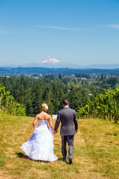 A bride and groom walk away from the camera at a vineyard at a winery in Oregon near portland and mount hood.