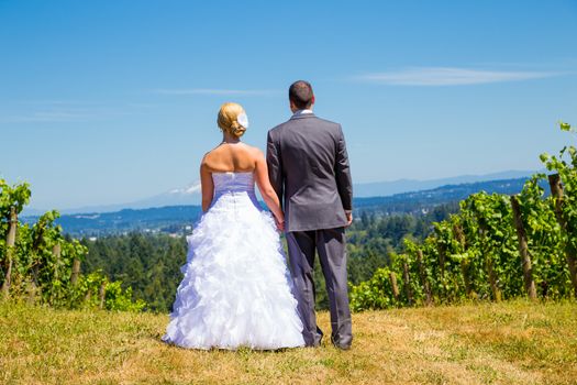 A bride and groom enjoy a view of mount hood in the background from this high elevation winery vineyard in Oregon just outside of Portland.